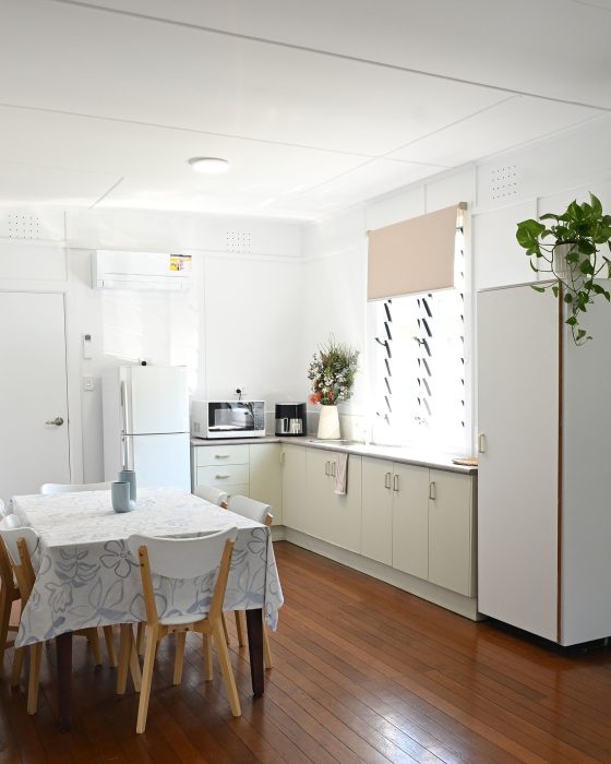 The kitchen area features pale green lower cabinets, a white countertop, and a white refrigerator on the left.