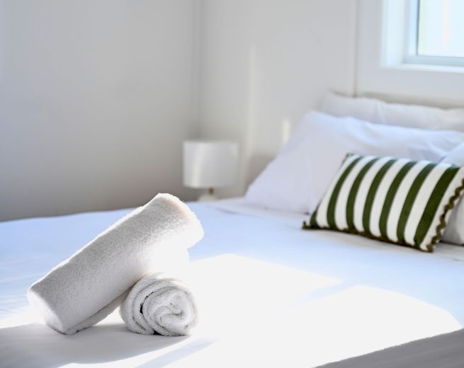 A Coral Cove Cabin with two rolled white towels are stacked at the foot of the bed.