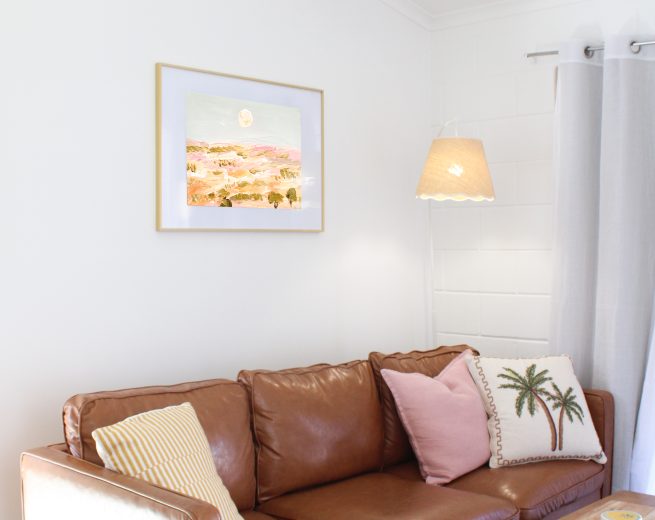 A brown leather sofa with decorative pillows sits in a bright living room