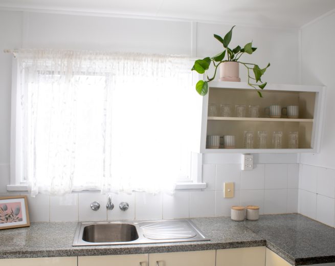 A bright kitchen corner featuring a stainless steel sink set in a granite countertop